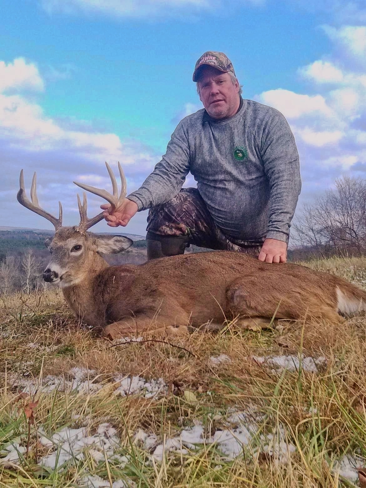 Bryan Flowers kneeling beside a deer outdoors